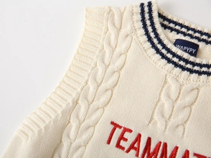 Detail of beige cable-knit vest featuring striped V-neck and TEAMMATE embroidery