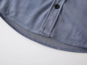 Macro shot of blue corduroy fabric texture and round hem details on kids shirt