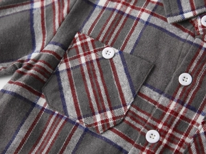 Detail of brushed flannel plaid fabric with a classic chest pocket and white button closure