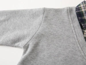 Detail of gray kids' sweatshirt featuring plaid collar patchwork and fine shoulder stitching