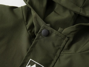 Detailed close-up of olive green kids hoodie collar with mountain embroidery and black snap