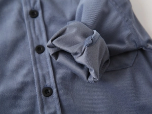 Detail of blue corduroy kids shirt showing button-up closure and soft ribbed fabric