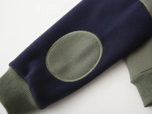Detail view of navy and olive green patchwork sleeves with elbow patch and ribbed cuffs