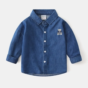 Detailed view of kids denim shirt collar with bear patch and white button closures