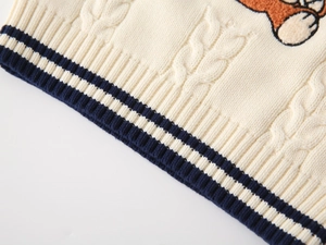 Detailed cable knit pattern on off-white kids' sweater vest with navy ribbed hem and bear