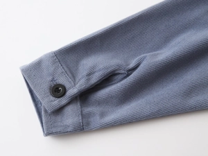 Close-up of ribbed corduroy shirt sleeve with matte black button and fine stitching