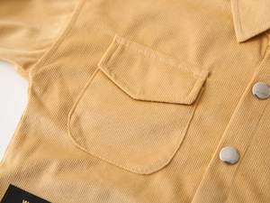 Detail of mustard corduroy shirt featuring metal snaps and a front flap pocket