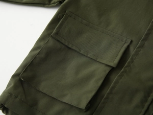 Detailed close-up of tactical flap pocket and reinforced stitching on green jacket