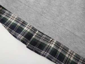 Detailed close-up of grey knit fabric stitched with classic blue and green plaid pattern