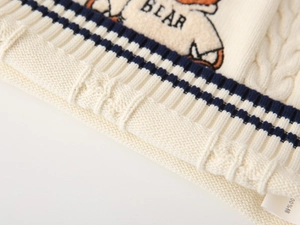 Detail showing 100% cotton material and cable knit texture with bear embroidery