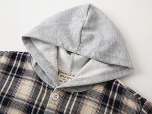 Detail of children's hooded plaid shirt with brand label and soft fabric texture