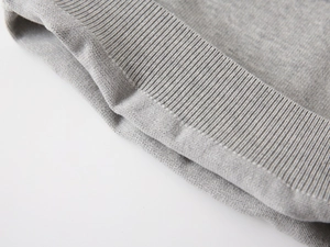 Macro view of light gray knit fabric showing the smooth texture and ribbed cuff detail