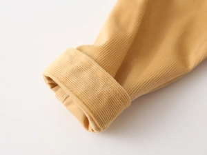 Detail of ginger yellow corduroy shirt cuff with vertical texture and fine stitching