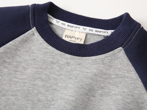 Détail de l'encolure du sweat raglan gris et bleu avec texture en maille côtelée