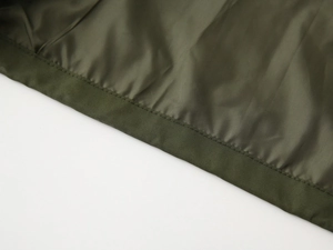 Close-up of military green toddler jacket showing reinforced double stitching on the hem