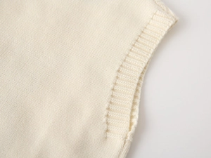 Close-up of beige knit vest showing ribbed edge detail and premium soft texture