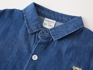 Detail shot of navy denim boy shirt collar with white button and cute bear embroidery