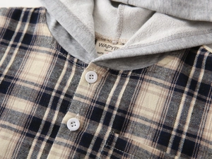 Detail view of the brown plaid fabric texture and gray knitted hood on the boy shirt