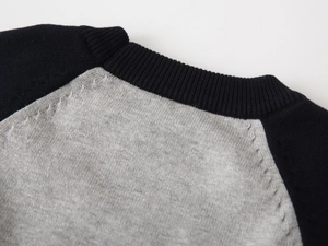 Close-up of raglan sleeve neckline on grey and navy knitted sweater for boys