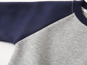 Détail du col rond côtelé et des manches raglan sur un sweat-shirt gris pour enfant en coton