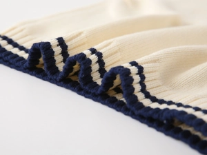 Detailed macro view of cream knitted fabric with navy blue striped ribbed edges