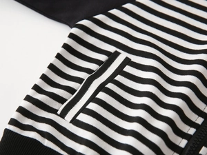 Close-up of black and white striped hoodie with zipper pocket and ribbed hem detail