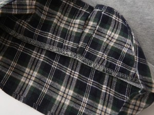 Close-up of green plaid fabric stitched to grey knit sweater with neat flatlock seams