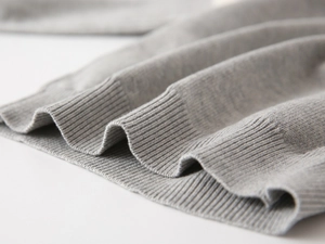 Macro view of grey knit sweater showing soft ribbed cuff texture and fine stitching detail