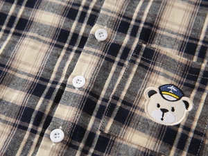 Detailed view of plaid shirt fabric with exquisite pilot bear embroidery and buttons