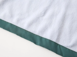 Detailed close-up of dark green satin edging and white plush fleece texture on jacket