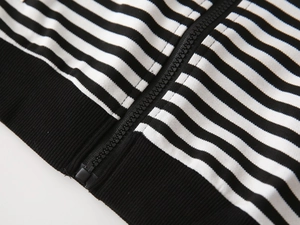 Detailed macro view of black and white striped hoodie with zipper and ribbed hemline