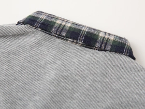 Detailed view of kids' gray sweatshirt with classic blue and green plaid shirt collar