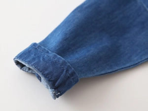 Detail shot of blue denim shirt cuff with neat double stitching and twill cotton texture