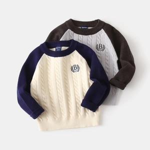 Close-up of cable knit texture and embroidered letter B on boy's knitted sweaters