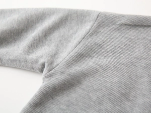 Close-up of fine gray knit fabric texture and high-quality flat seam stitching on shoulder