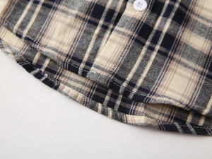 Detail view of cotton plaid shirt hem with navy blue patterns and white button