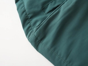 Detailed macro view showing the fine stitching and texture of the green kids jacket