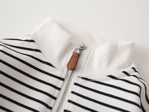 Close-up of white ribbed stand-up collar with metal zipper and brown leather puller