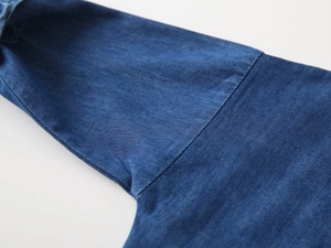 Detailed macro view of premium dark blue denim fabric texture and reinforced stitching