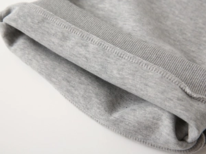 Détail des poignets côtelés gris et coutures fines sur un ensemble de survêtement