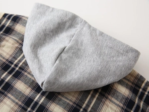 Detailed close-up of gray knitted hood and textured plaid fabric on toddler shirt