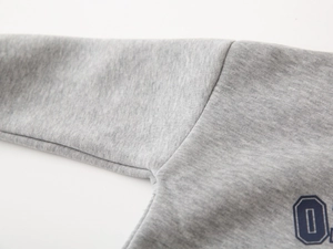 Macro shot of grey knitted sweatshirt fabric showing shoulder seams and sports print detail