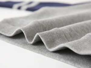 Détail de poignets en tricot gris avec rayures blanches sportives sur tissu bleu