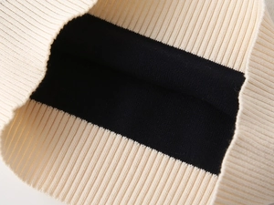 Close-up of beige ribbed collar and black knitted fabric texture on children's sweater