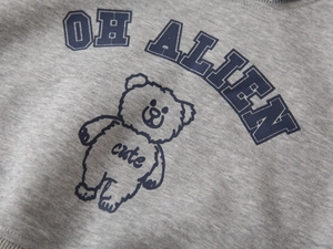 Detail of grey knit sweatshirt featuring a cute blue cartoon bear and OH ALIEN print