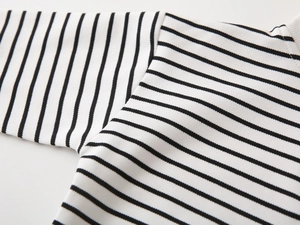 Detailed view of the black and white striped knit fabric and ribbed neckline of the sweatshirt