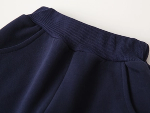 Détail de la taille élastique côtelée et des poches latérales du pantalon bleu marine garçon