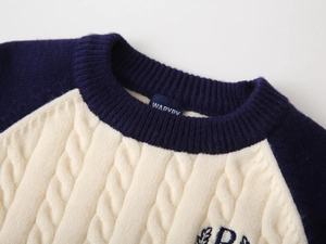 Close-up of cable-knit texture and letter embroidery on the stylish boys sweater