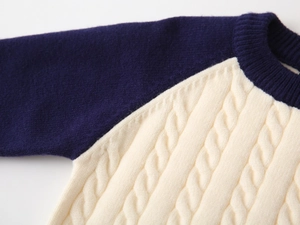 Detailed macro view of navy raglan sleeves and cream cable knit texture on boy sweater