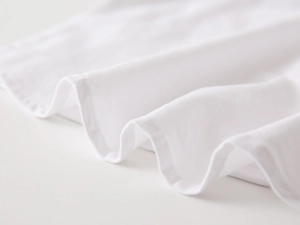 Detailed close-up of premium white knit fabric texture with fine stitched edge finish